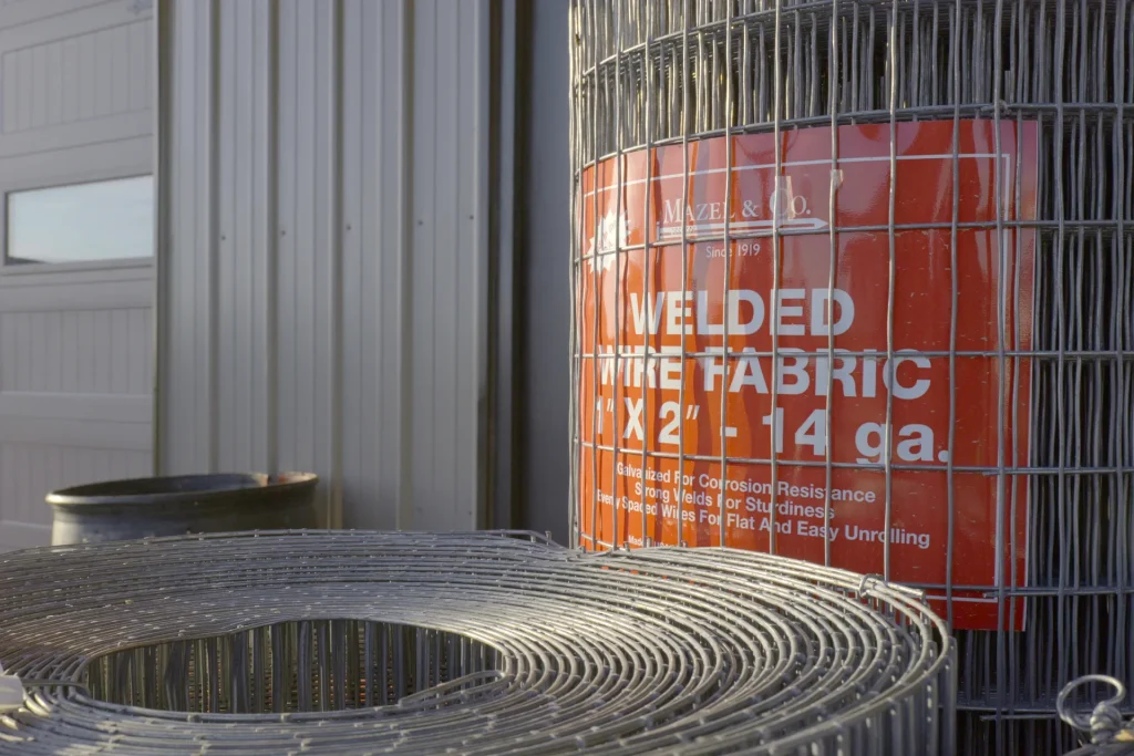 Rolls of Mazel & Co. galvanized welded wire fabric in 1" x 2" 14-gauge mesh, displayed outdoors at Dutchman’s Farm Supply in Versailles, Missouri.